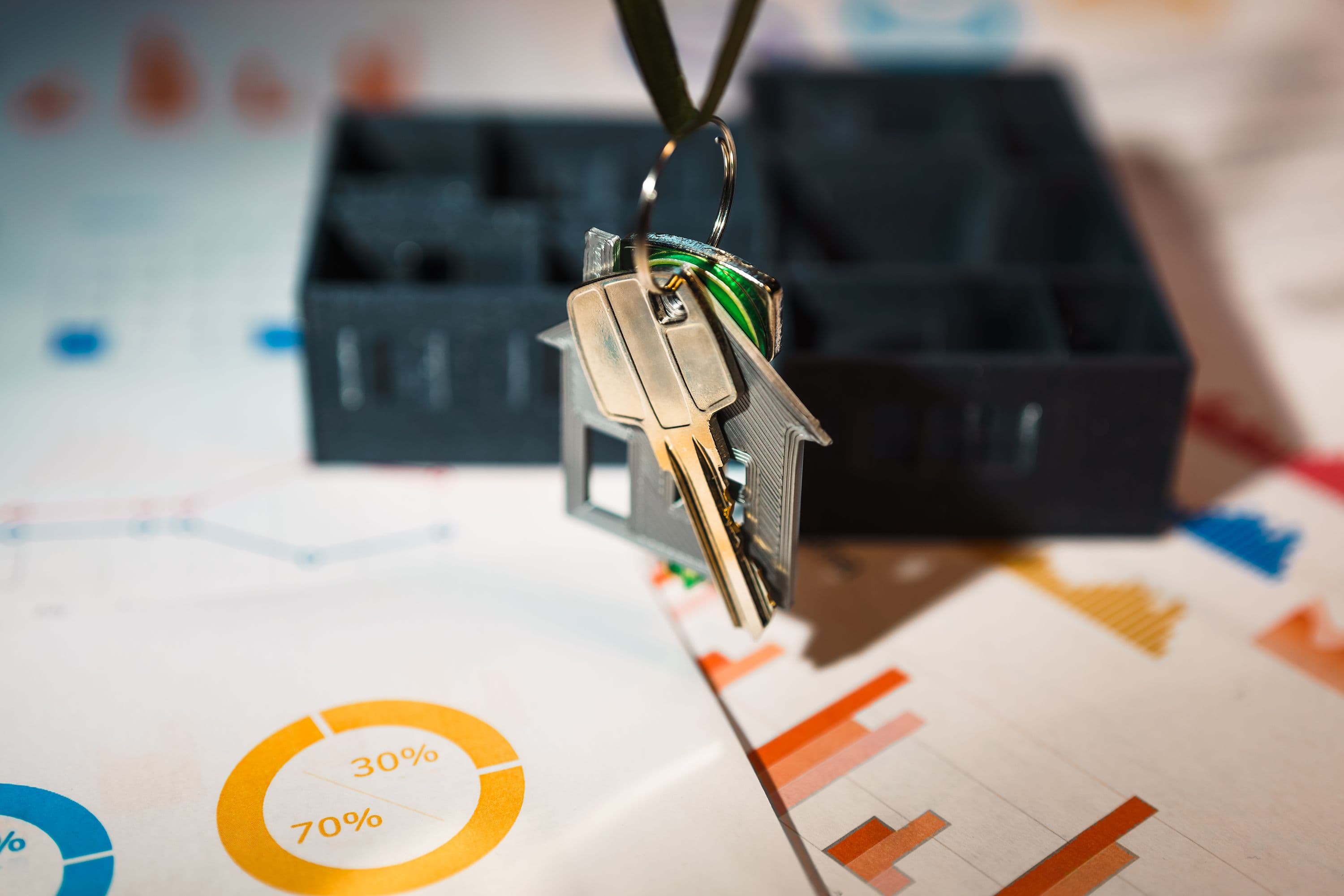 House keys beside a model home and financial paperwork