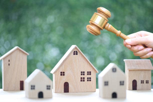 An auction gavel above model residential houses